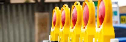 Reihe gelber Warnbaken mit roten Blinklichtern an einer Baustellenabsperrung