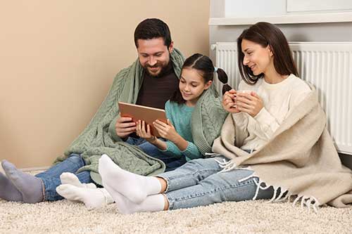 Familie vor einer Heizung sitzend