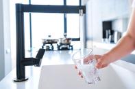 Eine Person gießt Wasser in ein Glas.