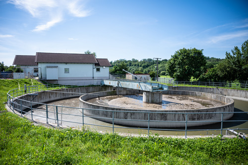Eine kreisförmige Betonstruktur mit einem Zaun drumherum - Kläranlage.