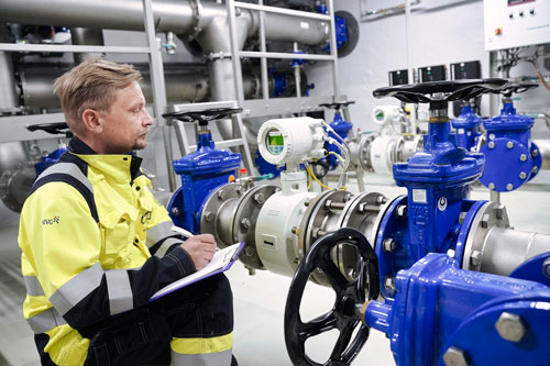 Ein Mann in einer gelben Jacke schreibt auf einem Klemmbrett.