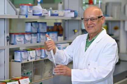 Ein Mann in einem weißen Kittel und Schutzbrille hält eine Pipette.