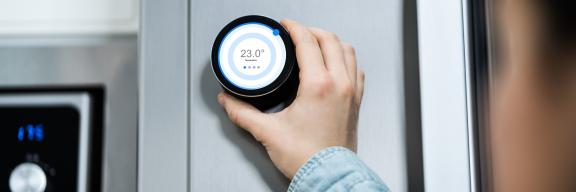 Eine Hand, die einen Thermostat dreht.