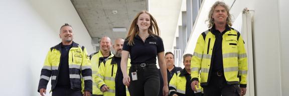 Sieben fröhliche Menschen in Arbeitskleidung.